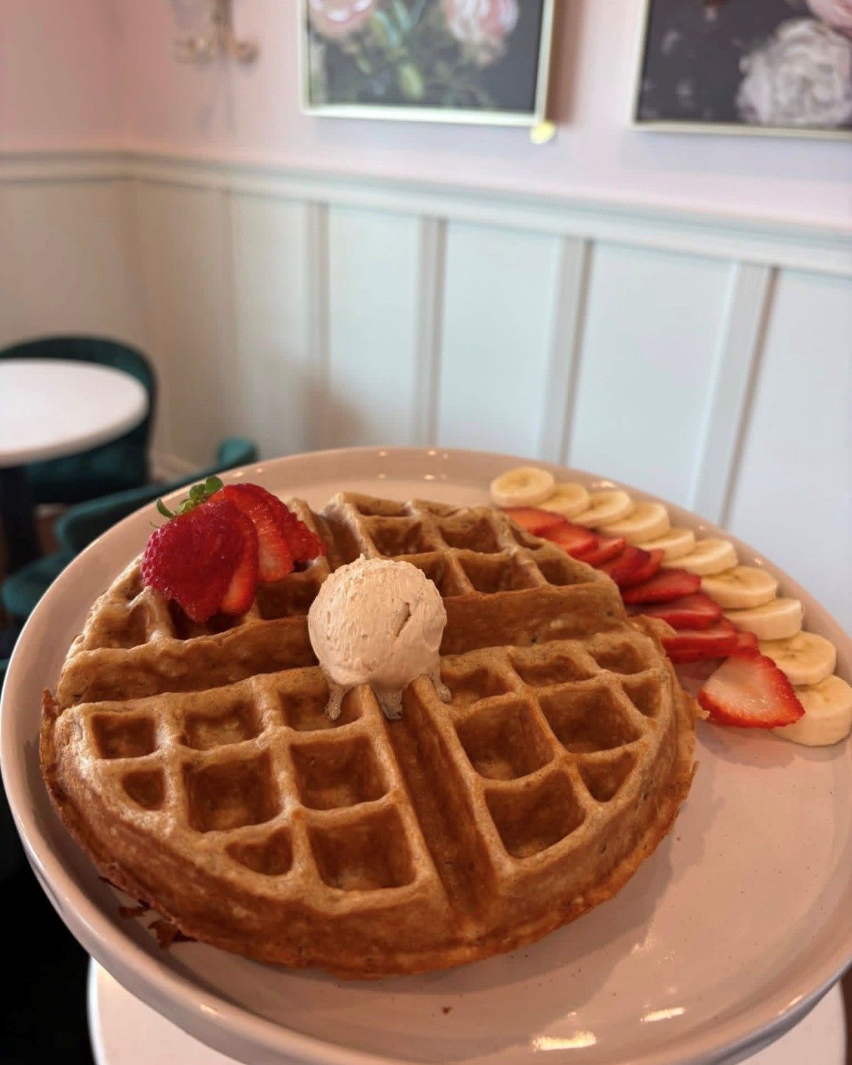 Waffle topped with strawberries and a scoop of ice cream on a plate in a cafe