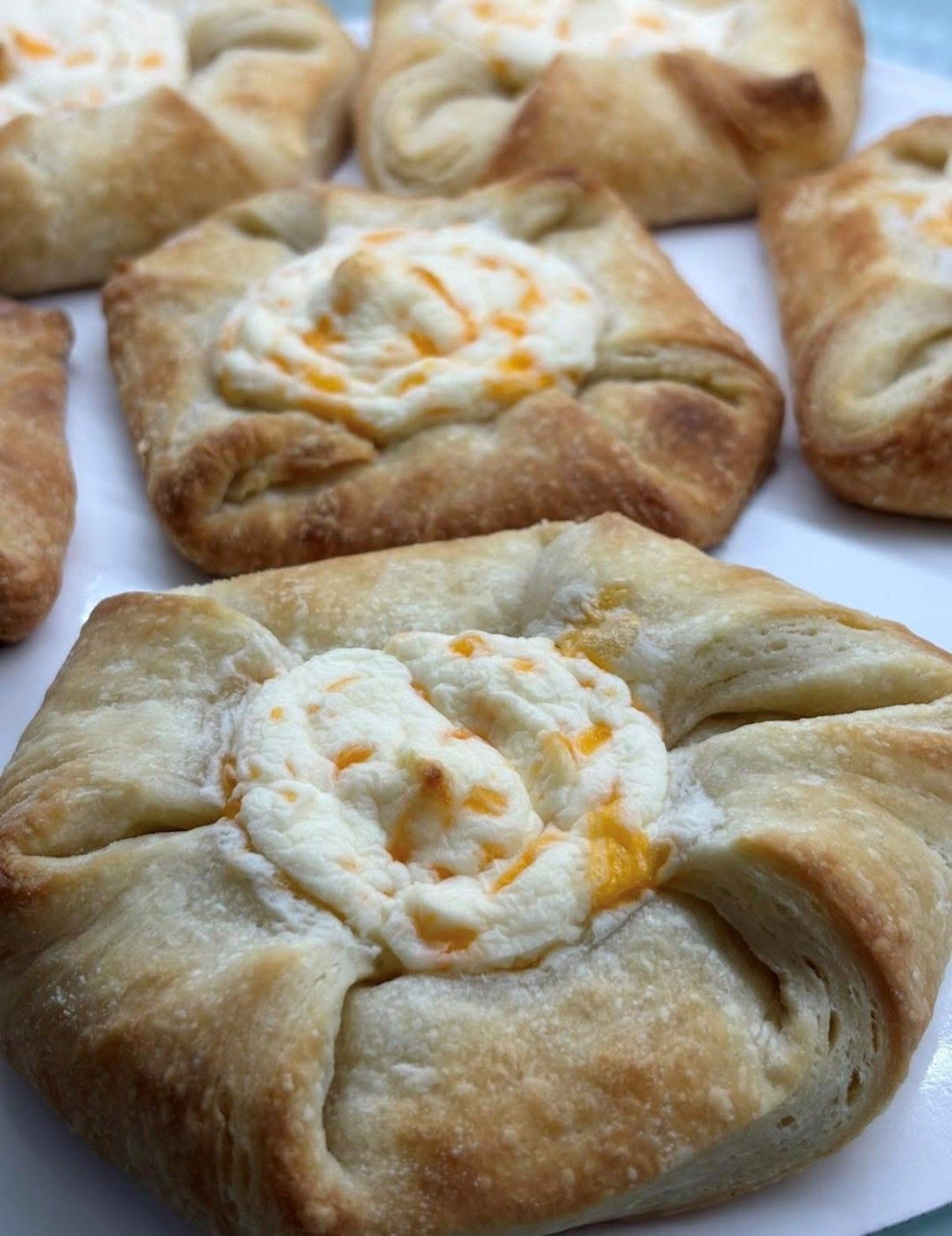 Golden-brown baked pastries with creamy filling on white parchment paper