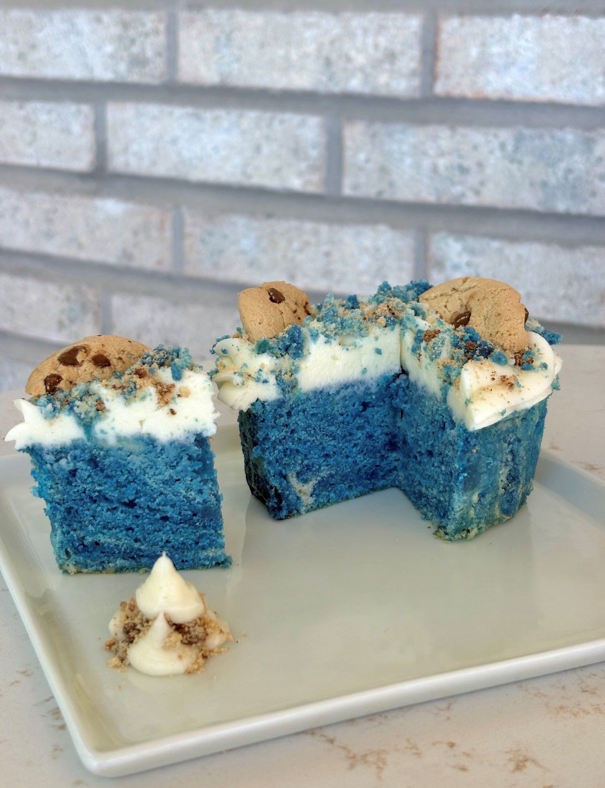 Blue cake slices with white frosting and cookie crumbs on a white plate