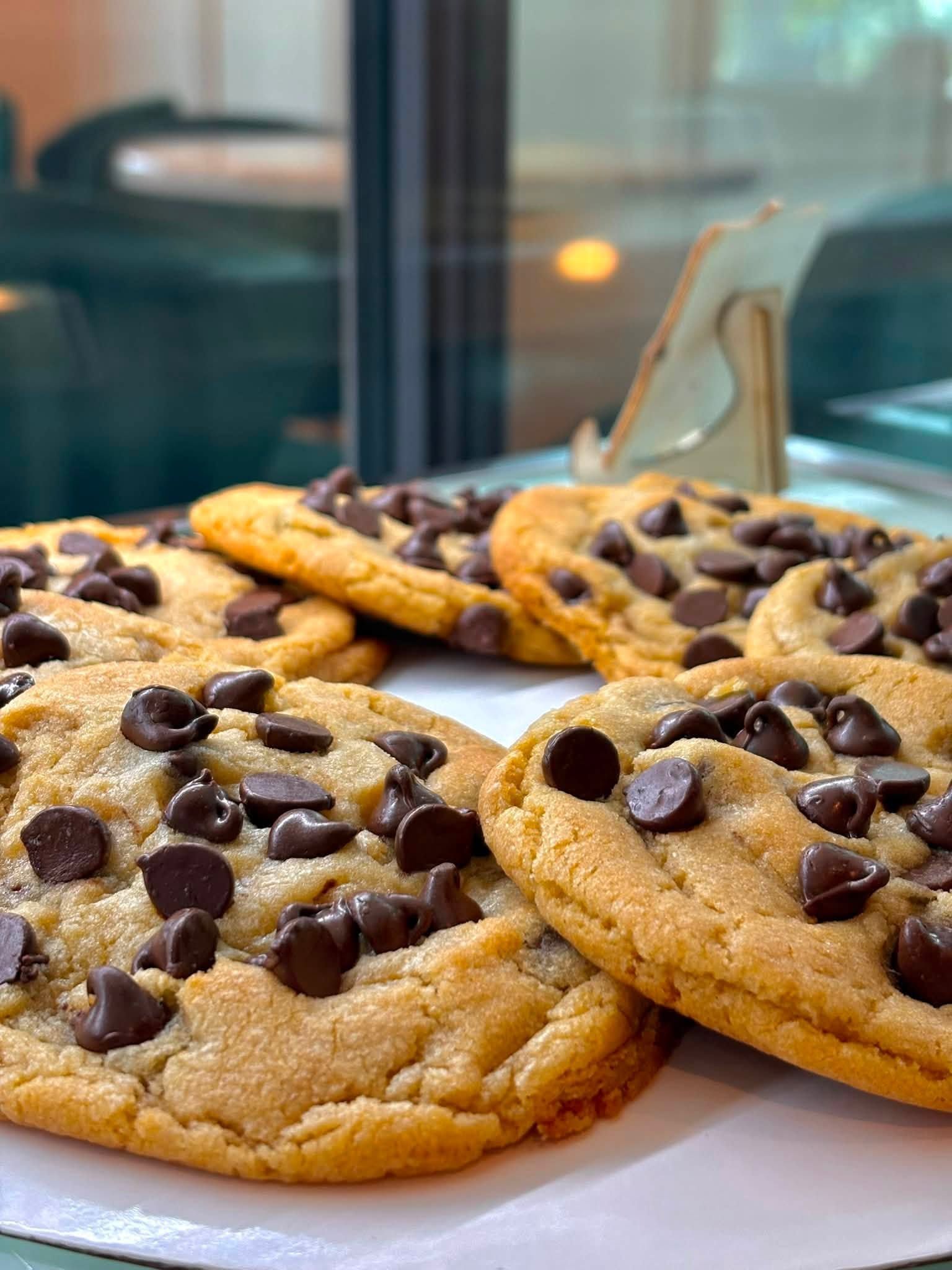 Chocolate chip cookies cooling on a tray, with several golden-brown cookies in the foreground.