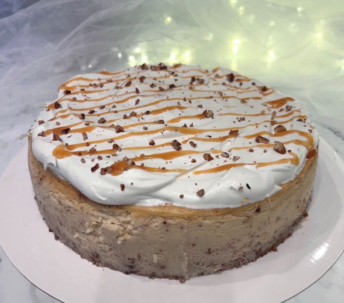 Round cake topped with white frosting and caramel drizzle on a white plate