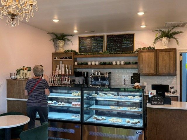Bakery café counter with pastries in glass display cases and a customer standing at the register