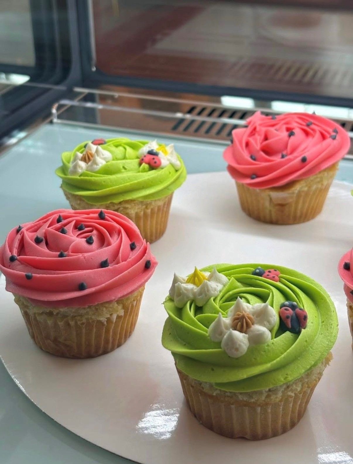 Assorted cupcakes with pink and green frosting on a white tray