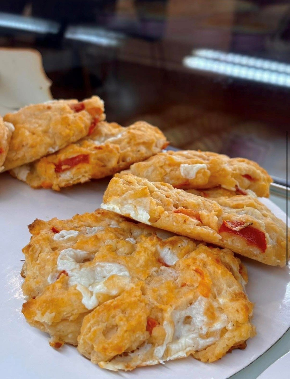 Plate of golden-brown pastries with red fruit filling and white icing on a table