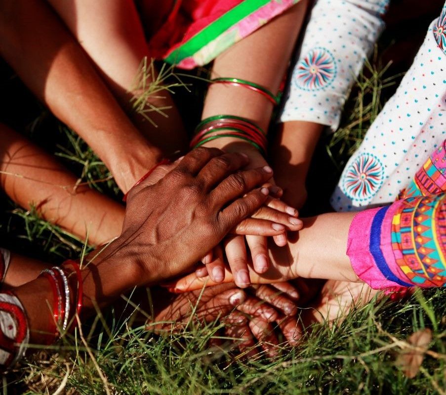 multiple people's hands held together in circle of friendship