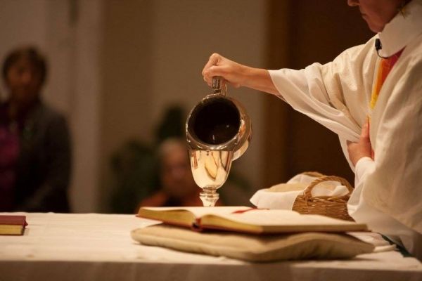 clergy pouring water into chalice