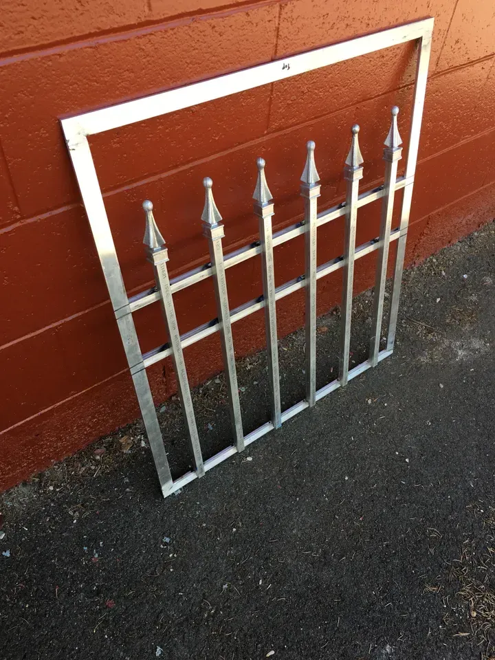 A metal fence is sitting in front of a red brick wall