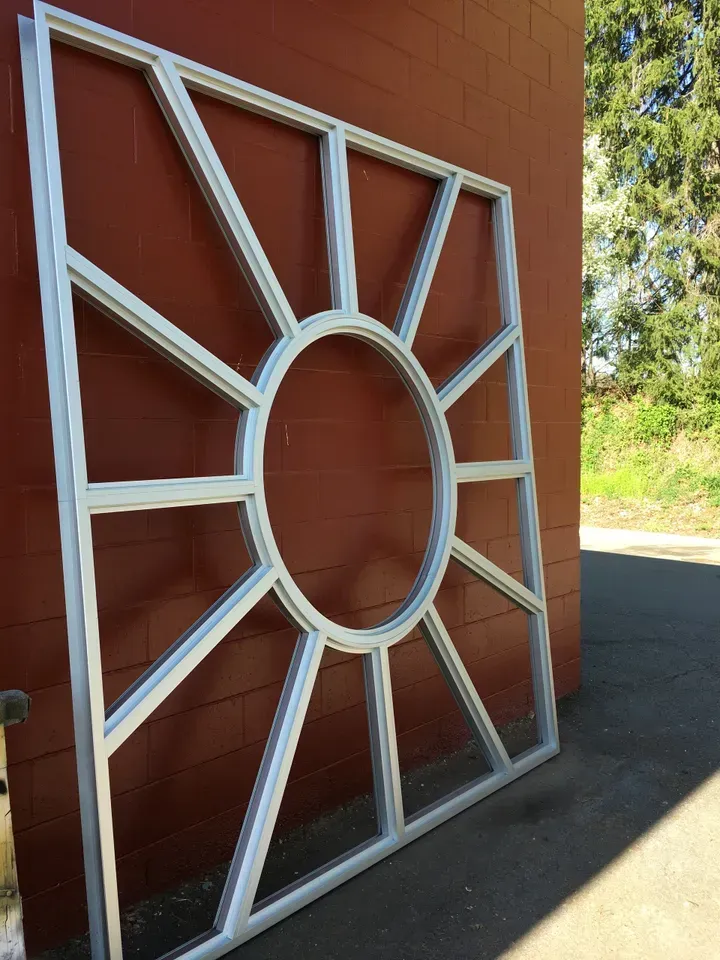 A square metal frame with a circle in the middle is sitting in front of a red brick wall.