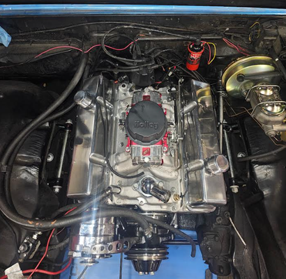 Car engine bay with polished silver intake and red throttle body on a blue body panel