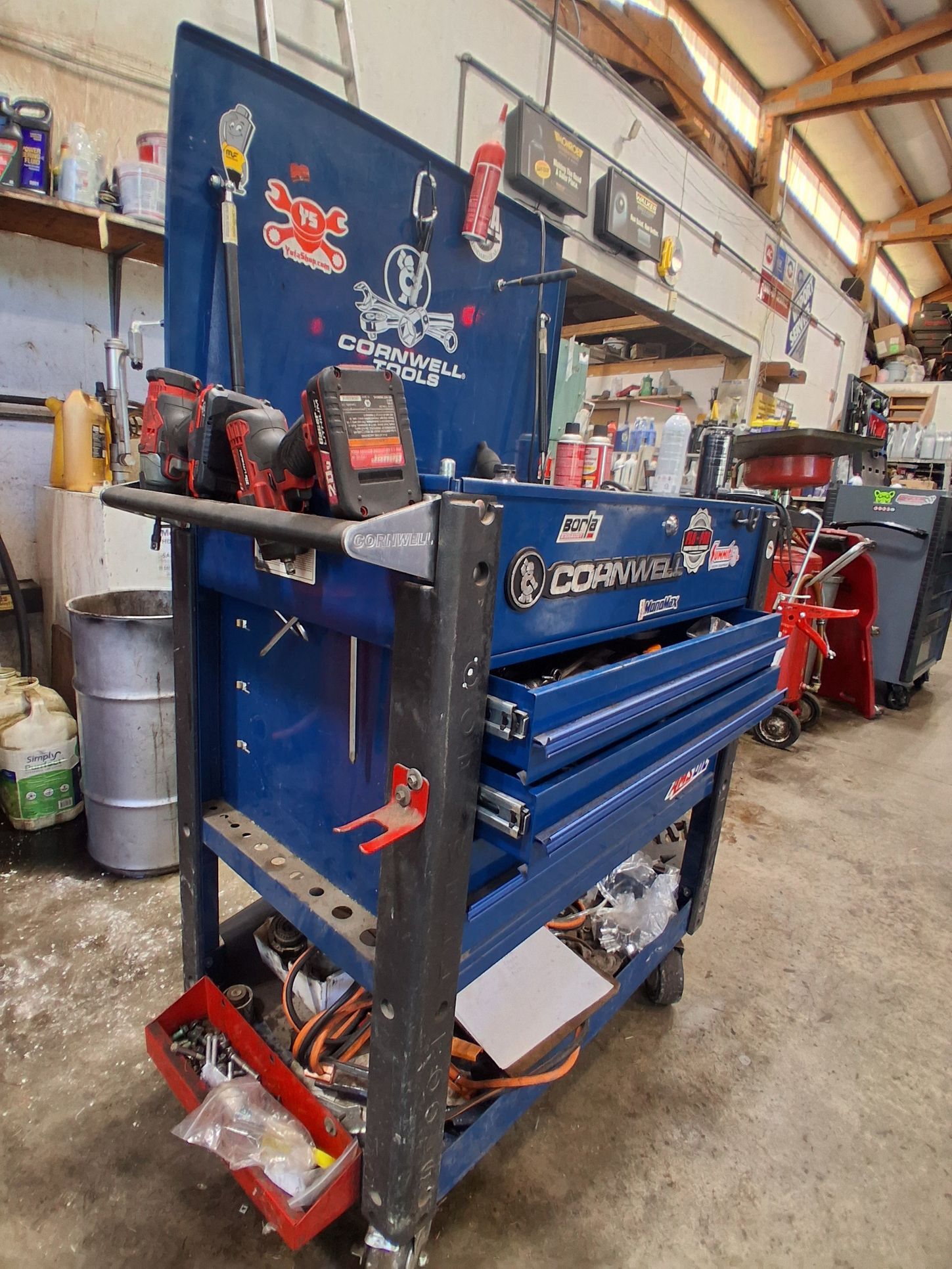 Blue industrial tool chest and parts organizer in a workshop aisle with red tools and shelves