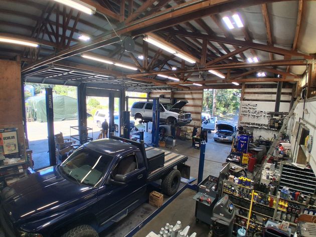 Auto repair shop with blue pickup truck, car lift, tools, and open garage doors