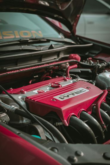 Close-up of a car engine bay with a red engine cover and visible hoses under the hood.