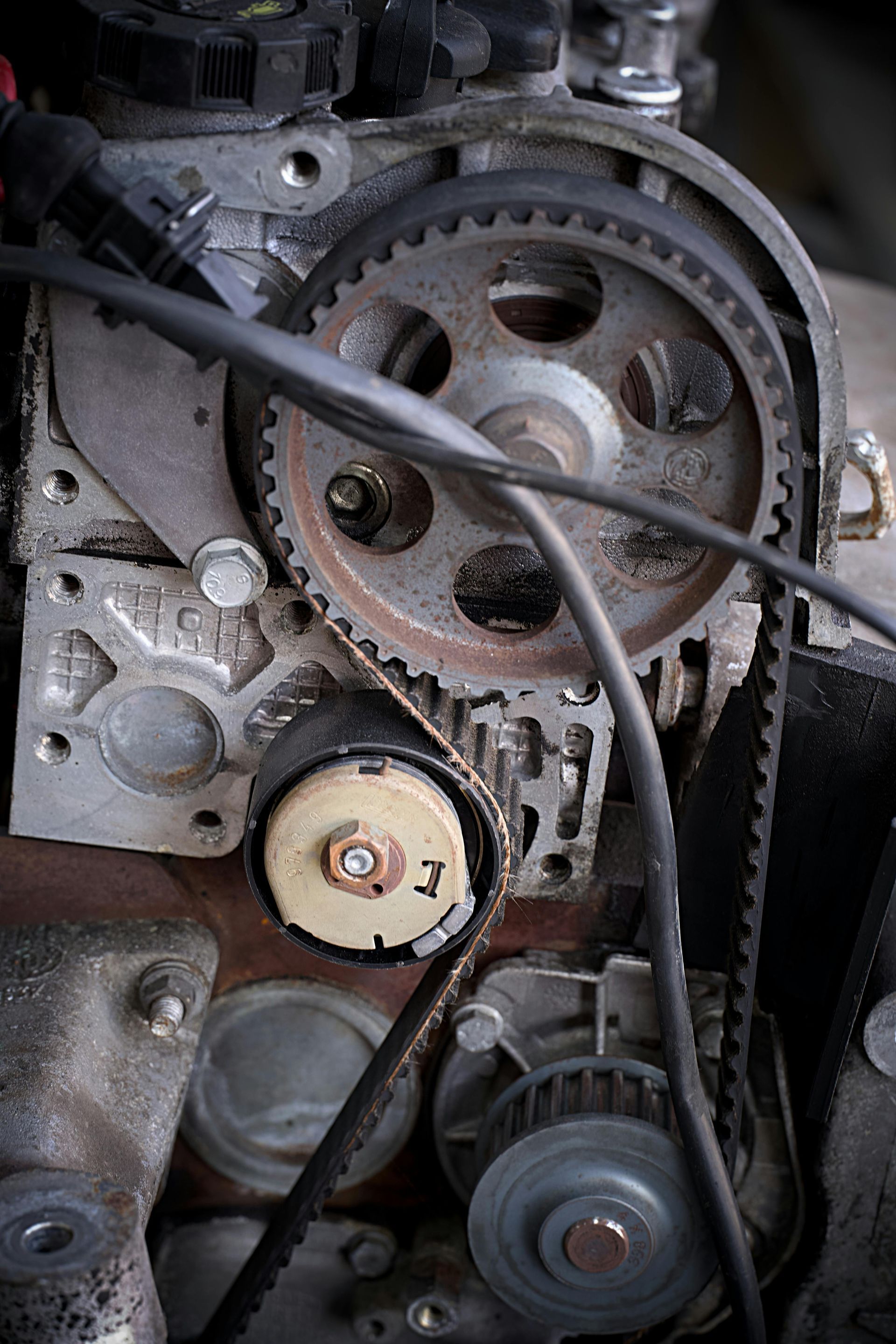 Close-up of a car engine timing belt and pulleys with visible gears and metal components