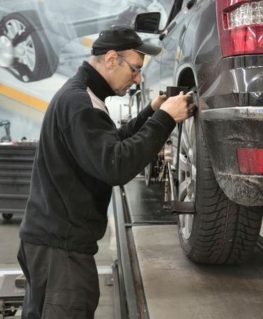 Mechanic inspecting a black SUV’s wheel in an auto repair shop