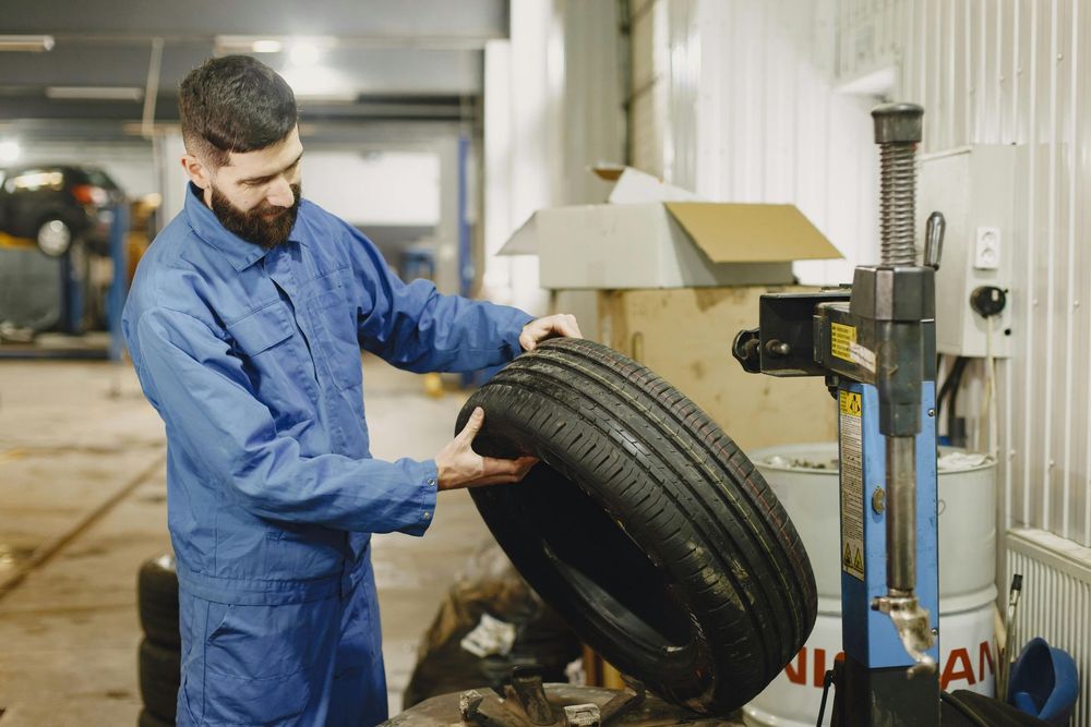 Mechanic inspecting a tire in a workshop beside a balancing machine