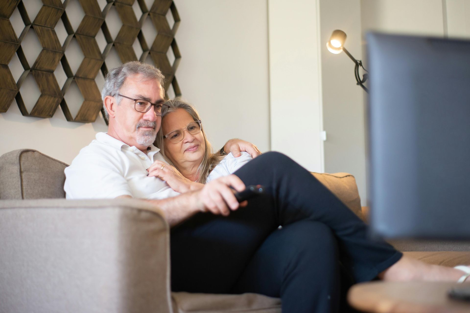 A man and woman are sitting on a couch watching television.