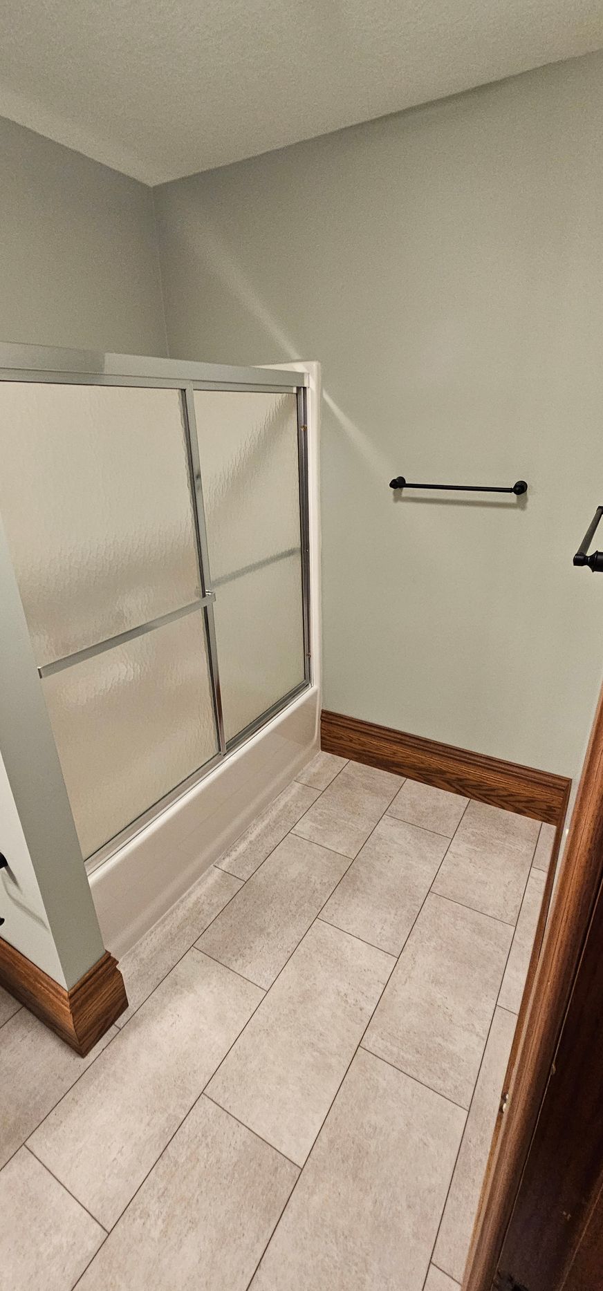 Small bathroom with a shower/tub, beige tile floor, gray walls, and a towel bar.