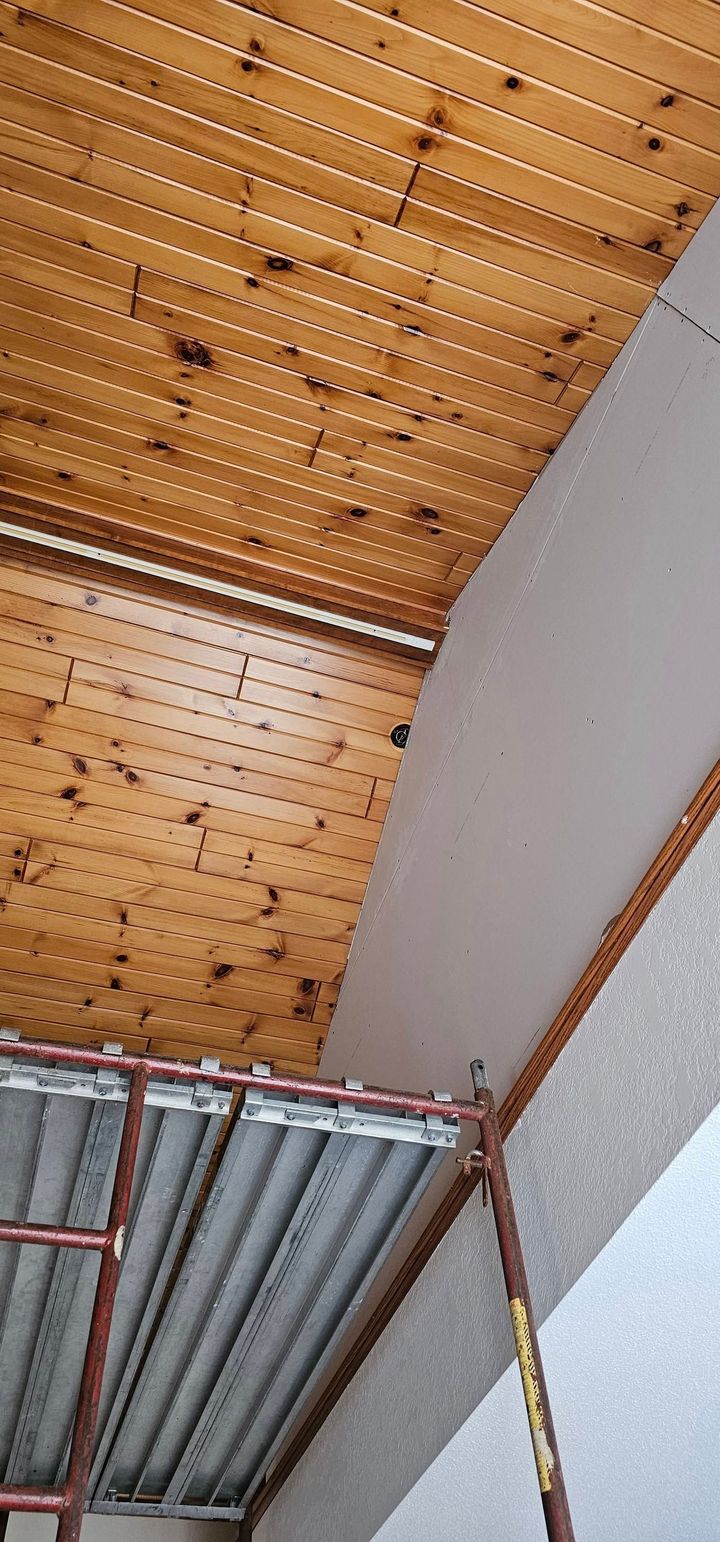 Wooden arched ceiling with exposed metal beams and a gray wall inside a building