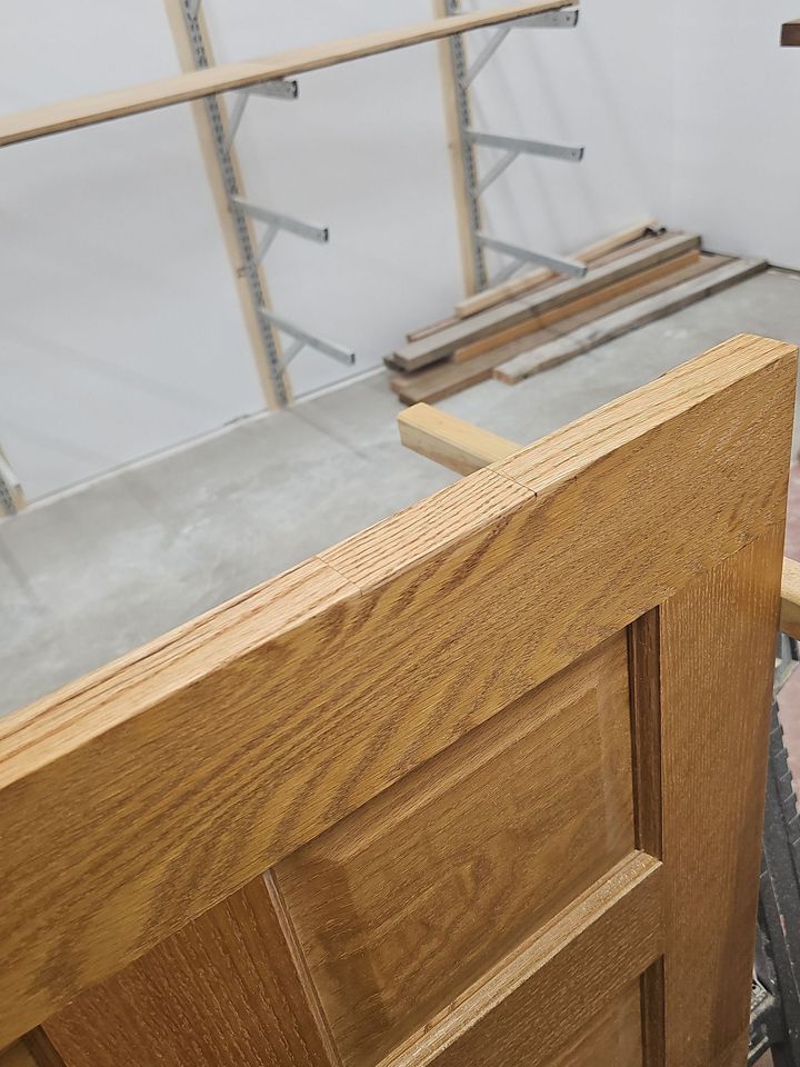 Wooden door or panel leaning on a balcony railing in a bright indoor stairwell.