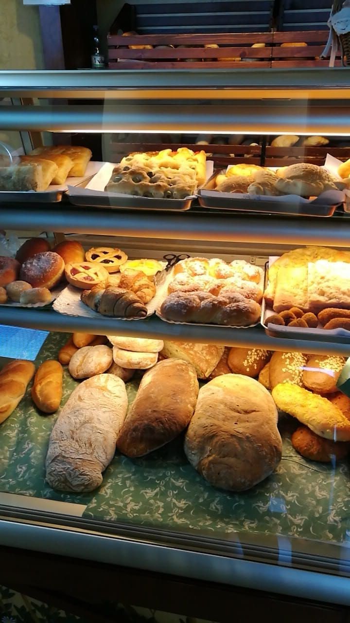 Vetrina da panetteria con assortimento di pane, pasticcini e panini su ripiani illuminati