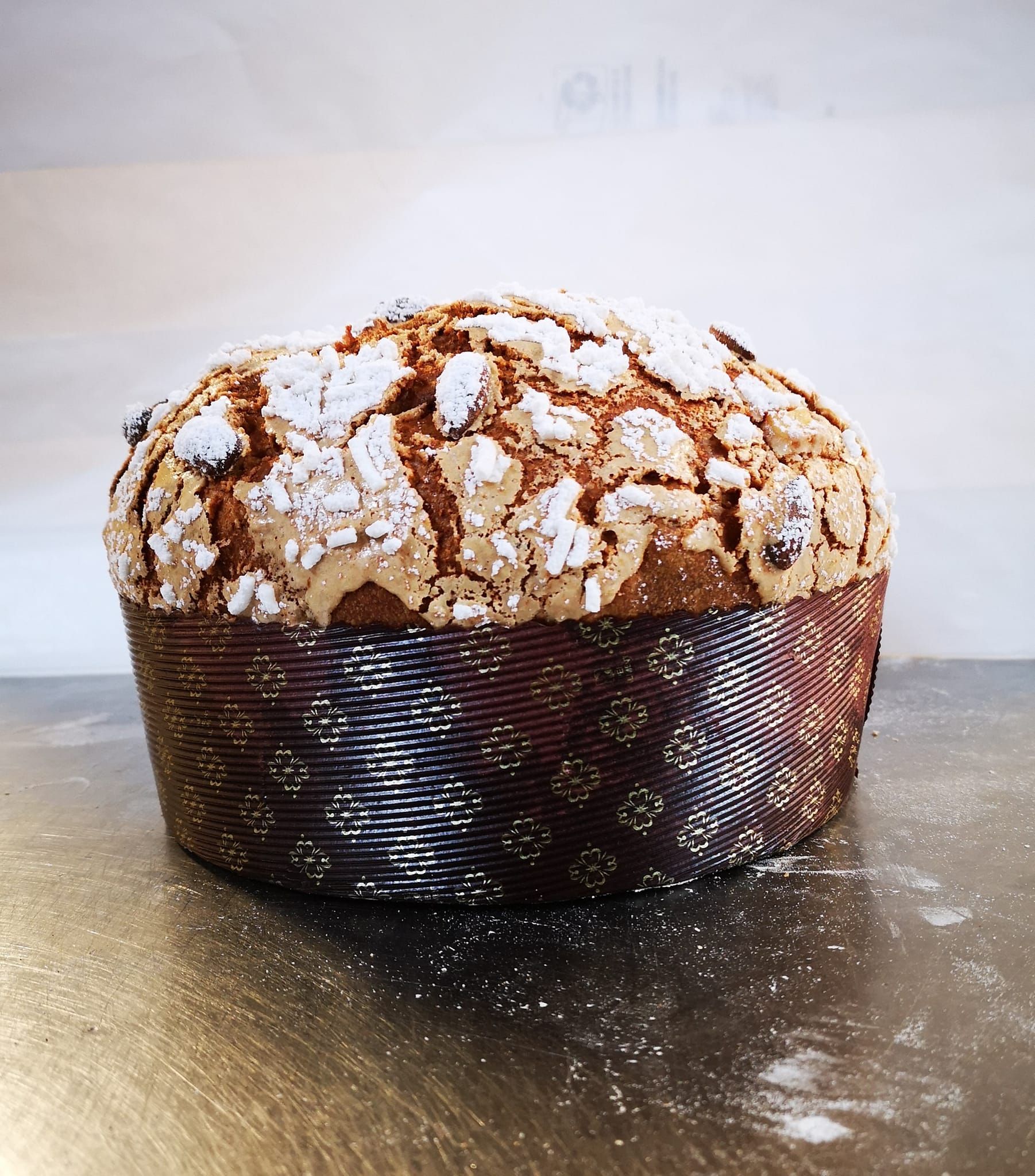 Muffin ricoperto di zucchero a velo in un involucro di carta scura su una superficie grigia