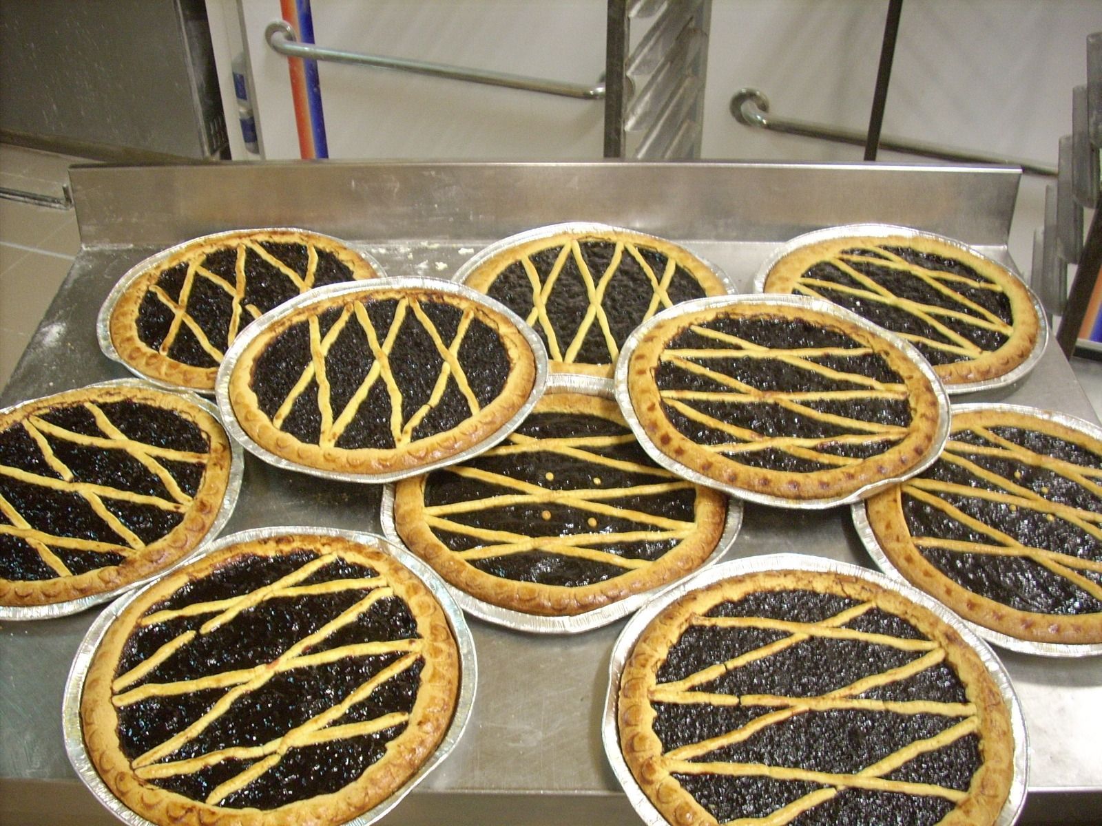 Vassoio di pasticcini rotondi con ripieno al cioccolato e decorazione a griglia gialla, in una teglia di metallo.