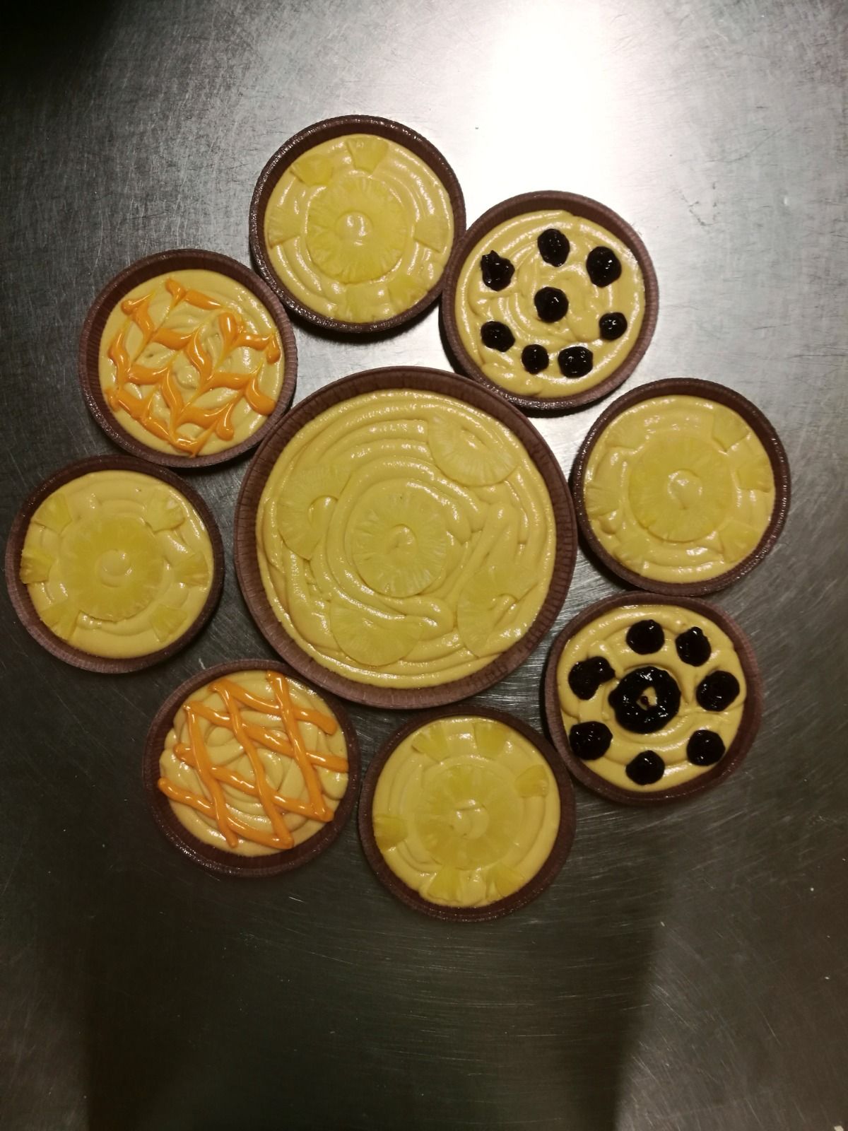 Biscotti assortiti con glassa gialla, disposti in cerchio su una superficie scura.