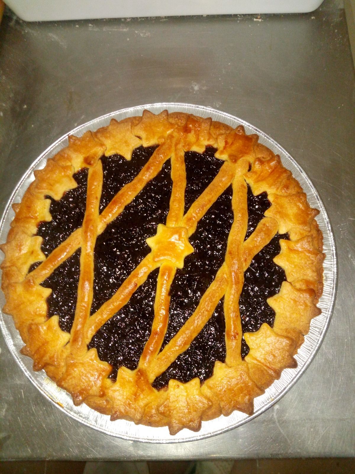 Torta rotonda di frutti di bosco con crosta a grata, su una teglia da forno.