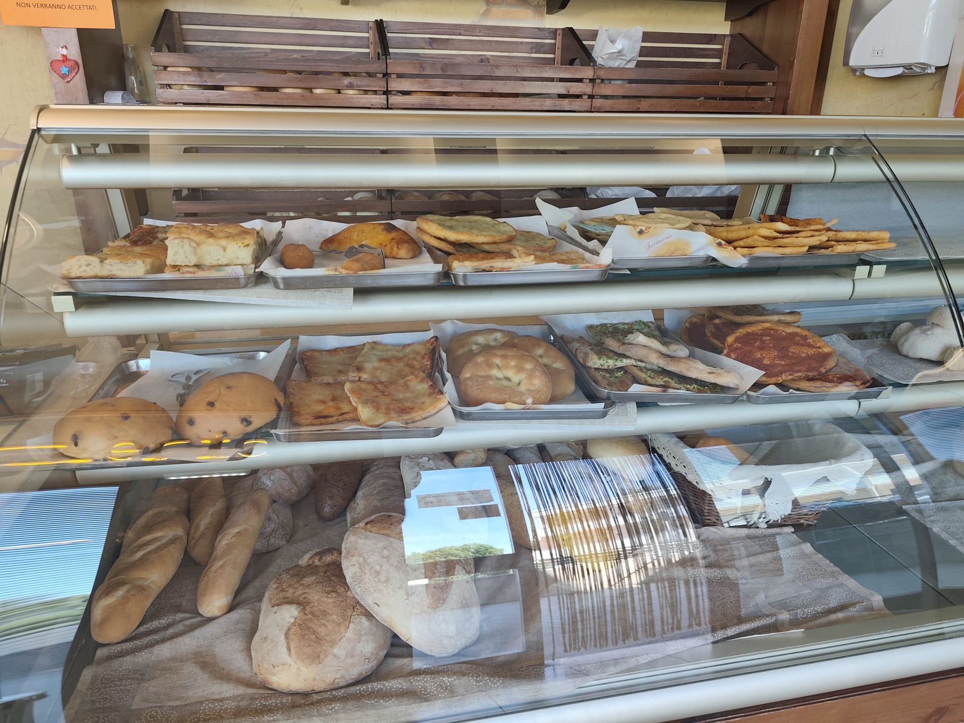 Vetrina da forno con assortimento di pasticcini, biscotti, pagnotte e pane confezionato sugli scaffali