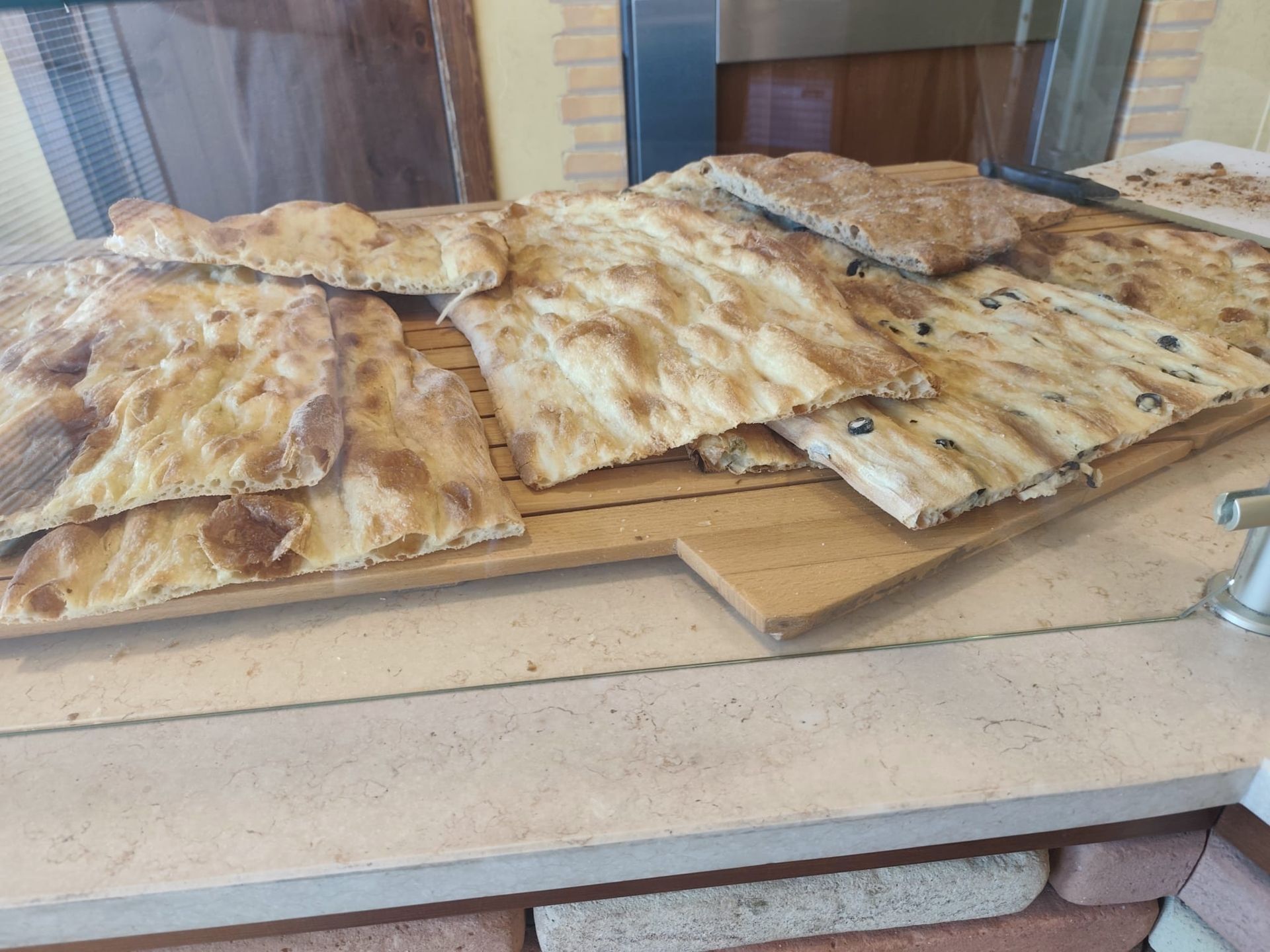 Vassoio di focacce e pasticcini assortiti esposto su un bancone in una panetteria.