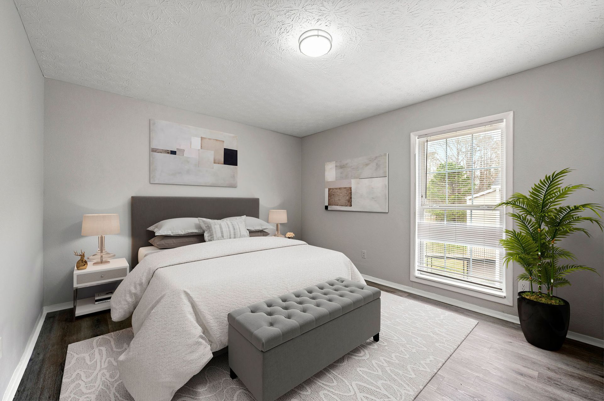 Bright gray bedroom with a bed, tufted bench, nightstand, window, and potted plant