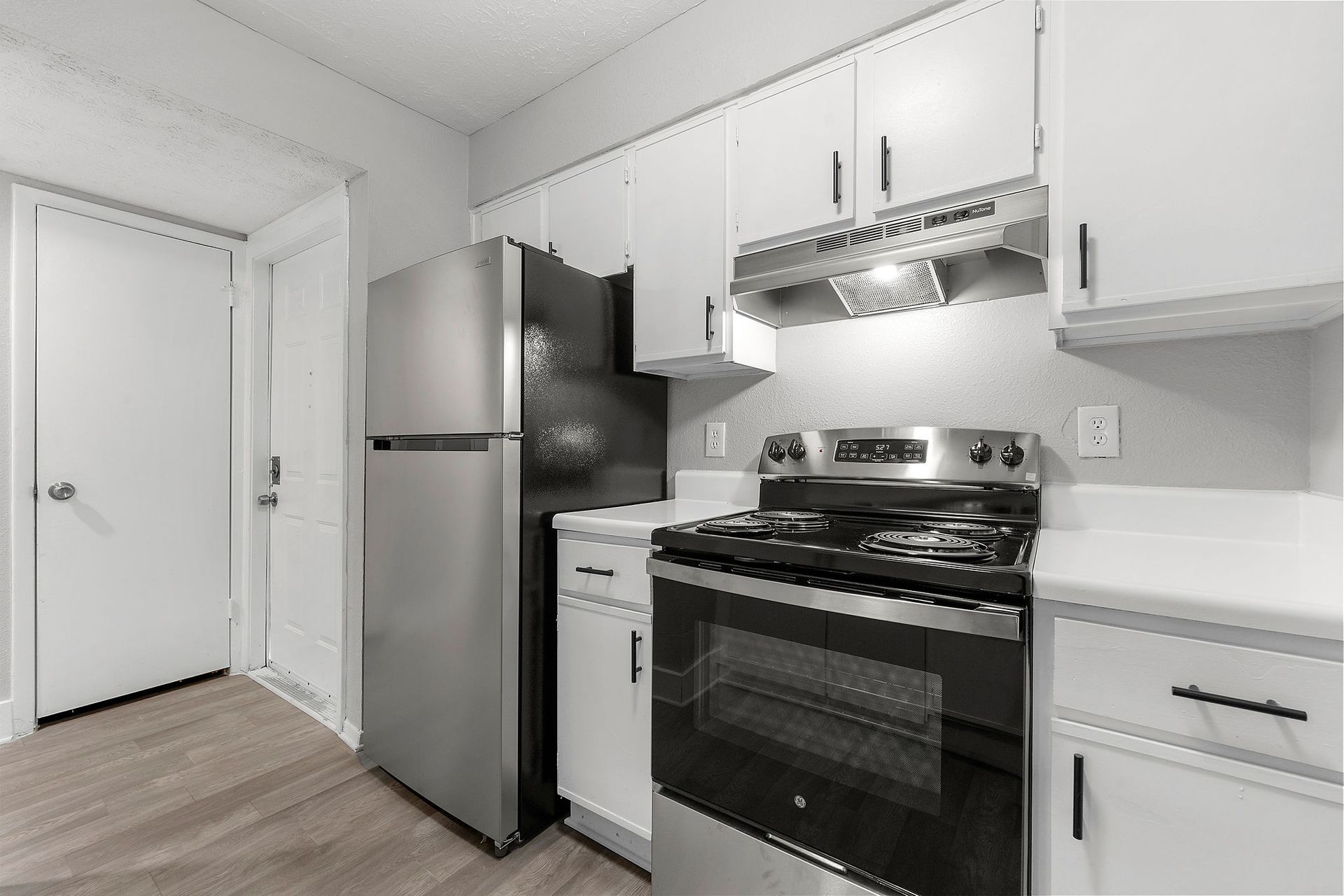 Bright hallway with light wood floors, gray walls, and a white vanity with mirror in a bathroom nook.