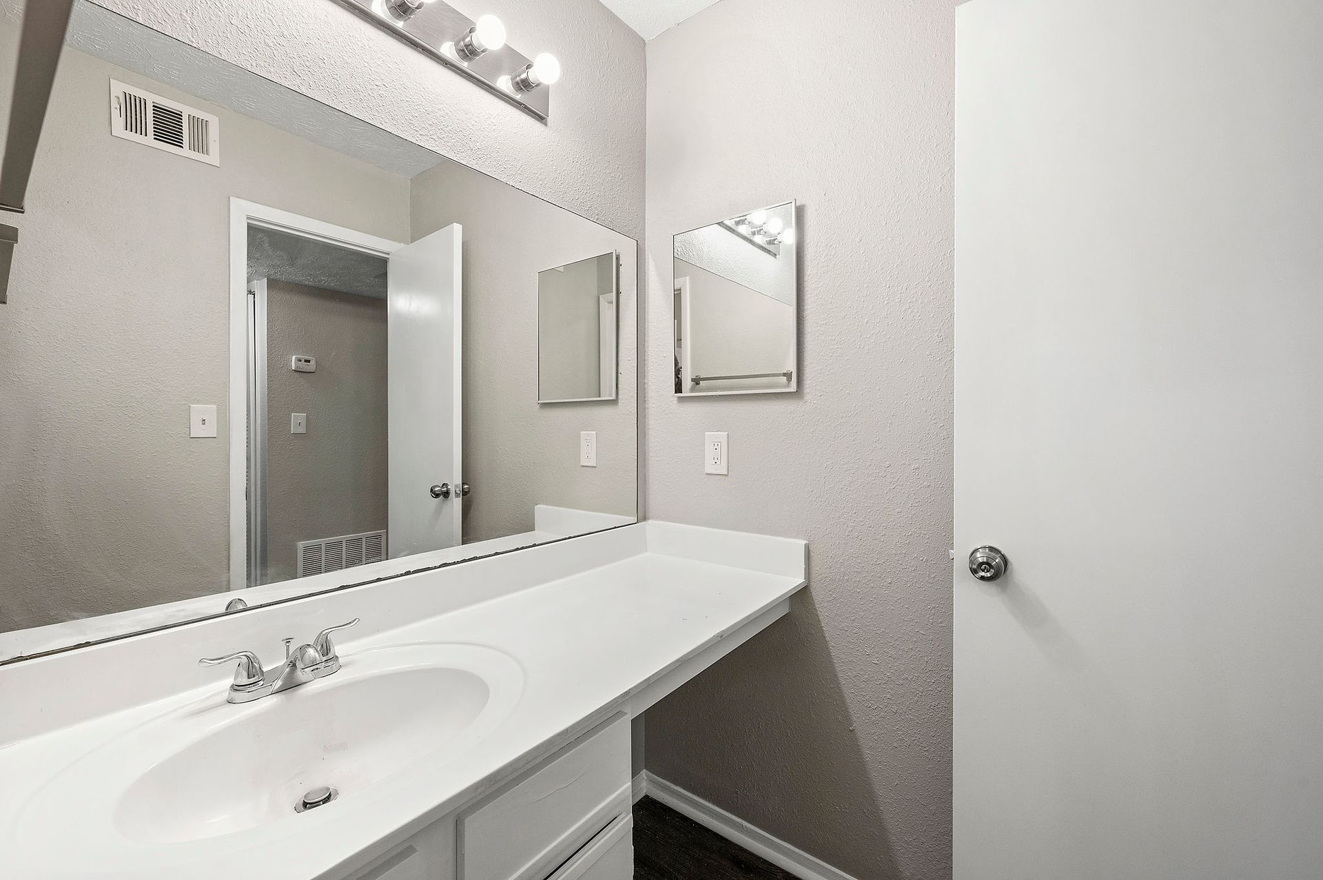 Bright modern bathroom vanity with large mirror, white sink, and gray walls