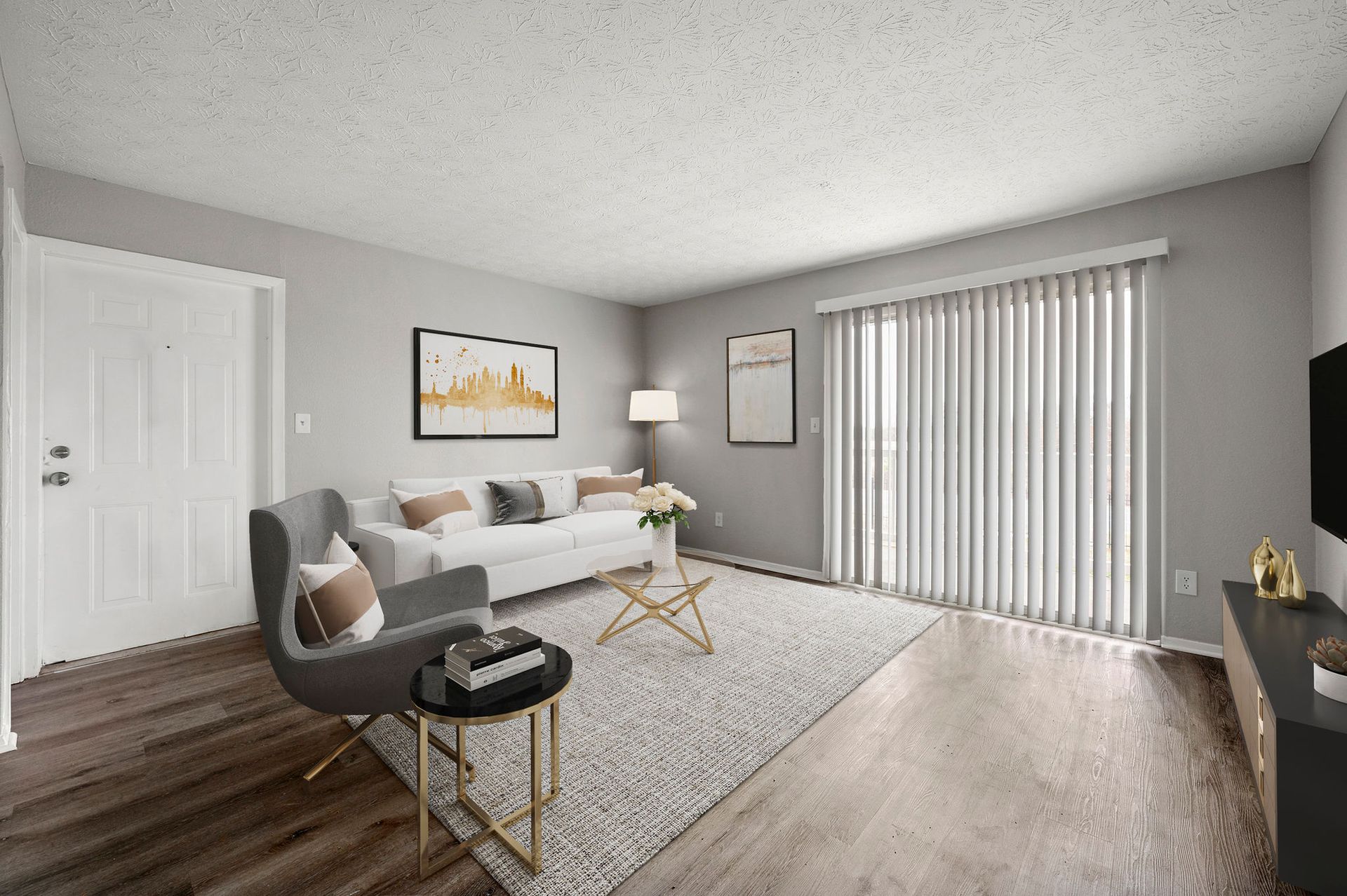Bright living room with gray sofa, rug, lamp, coffee table, and sliding glass doors with vertical blinds.