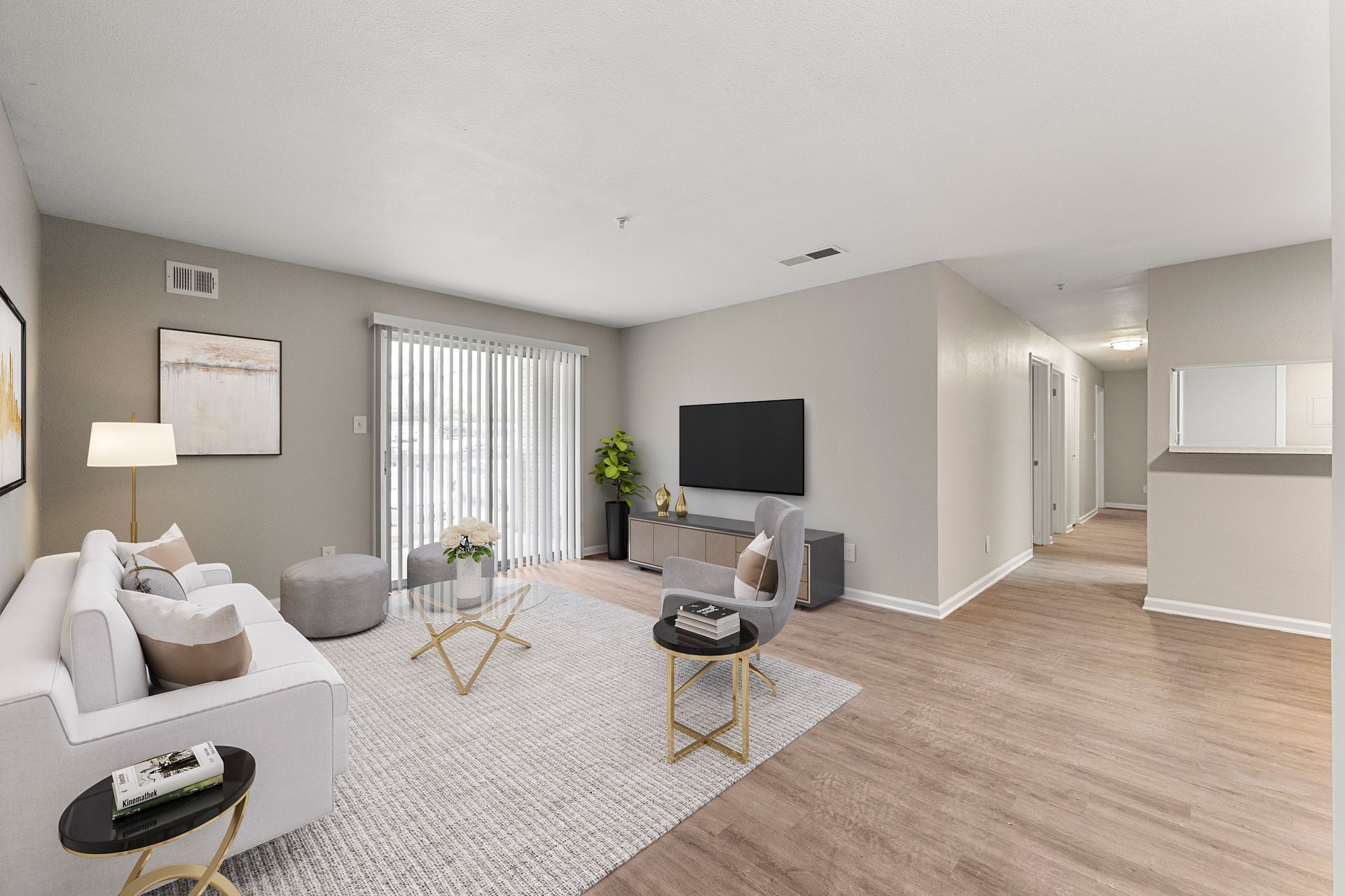 Bright modern living room with white sofa, TV, gray chairs, and wood floors.
