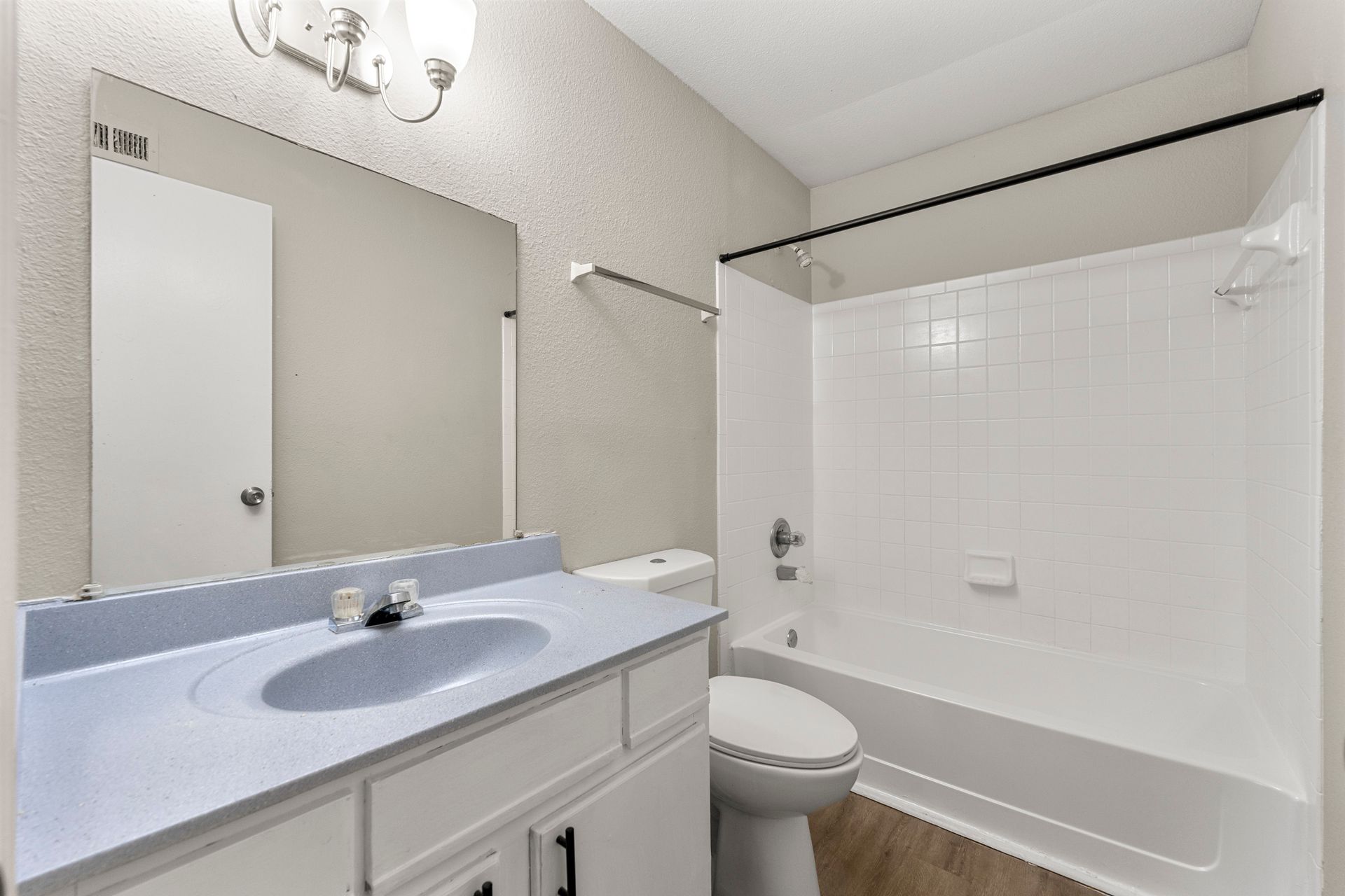 Bright white bathroom with vanity sink, mirror, toilet, and shower-tub combo.