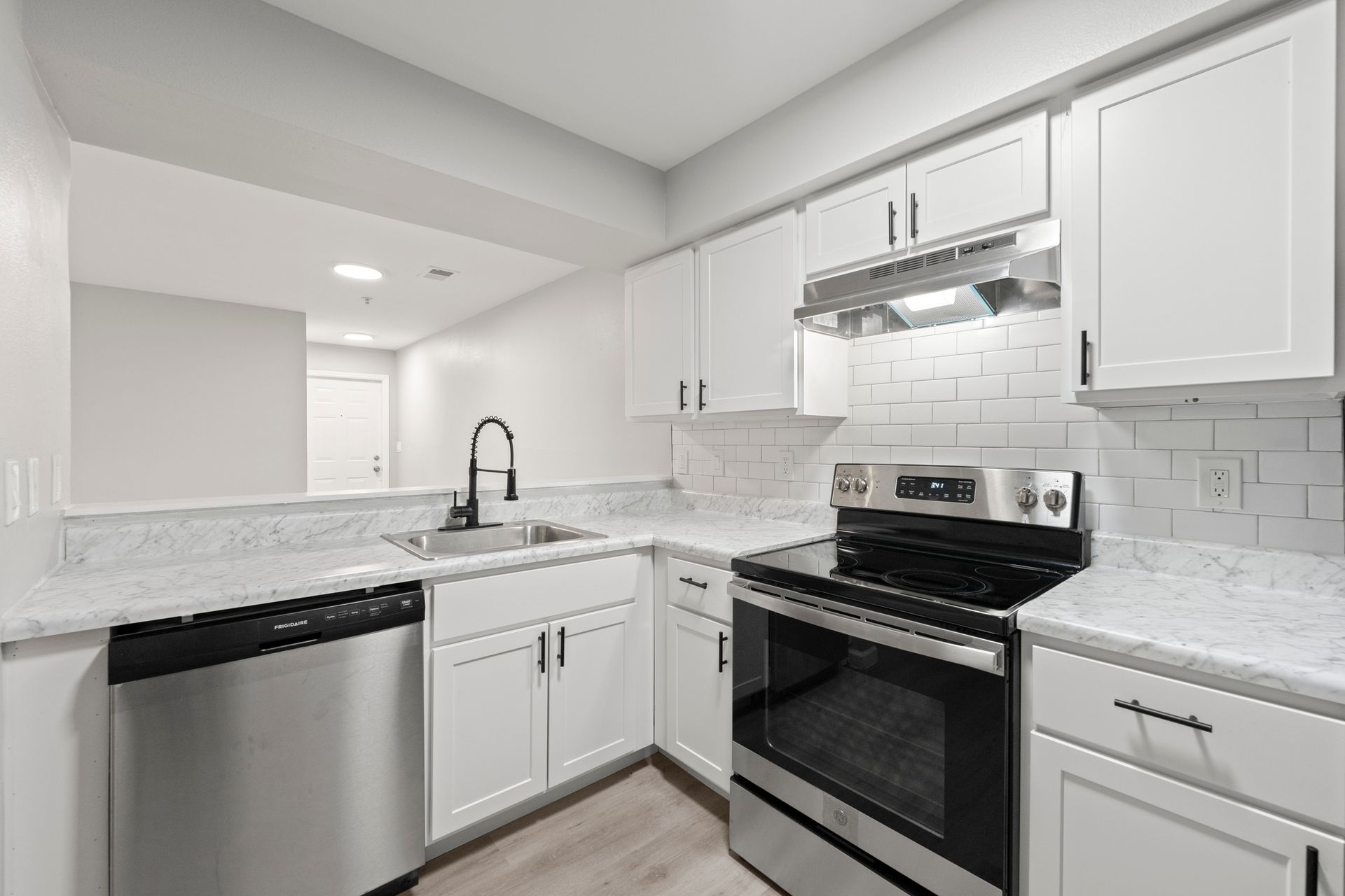 Bright modern kitchen with white cabinets, stainless appliances, and granite countertops