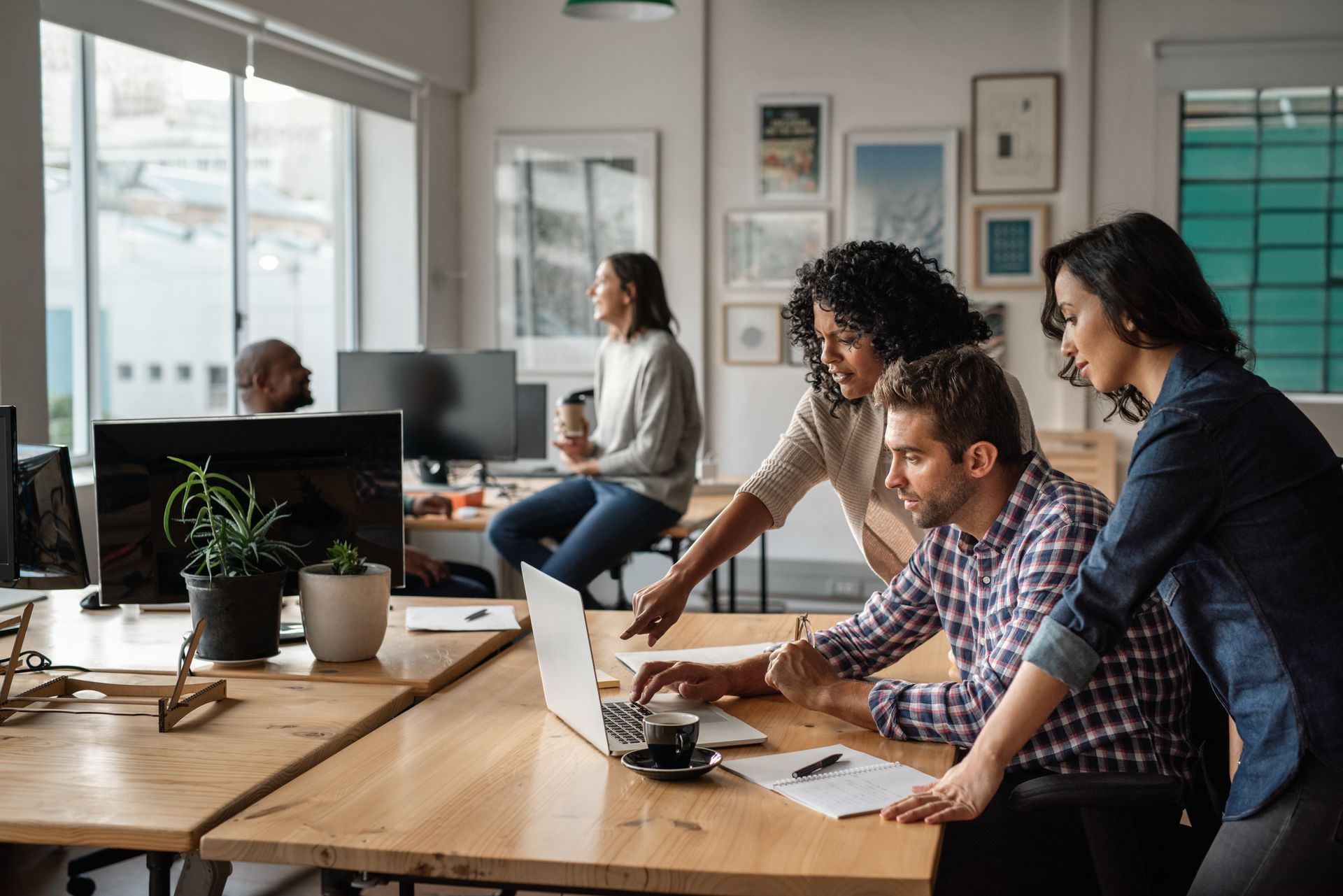 People collaborating around a laptop in a bright office workspace