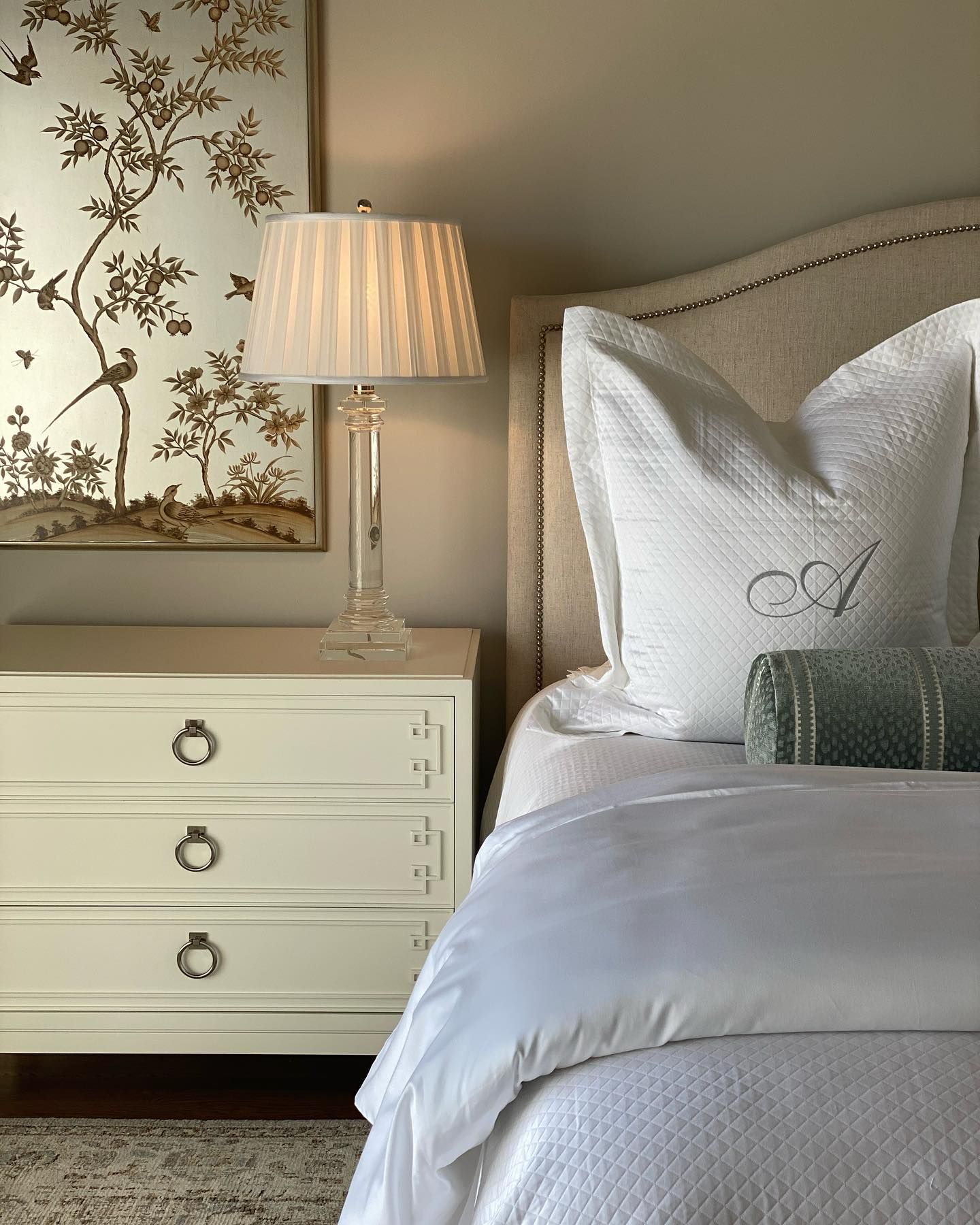 A bedroom with a bed a lamp and a dresser