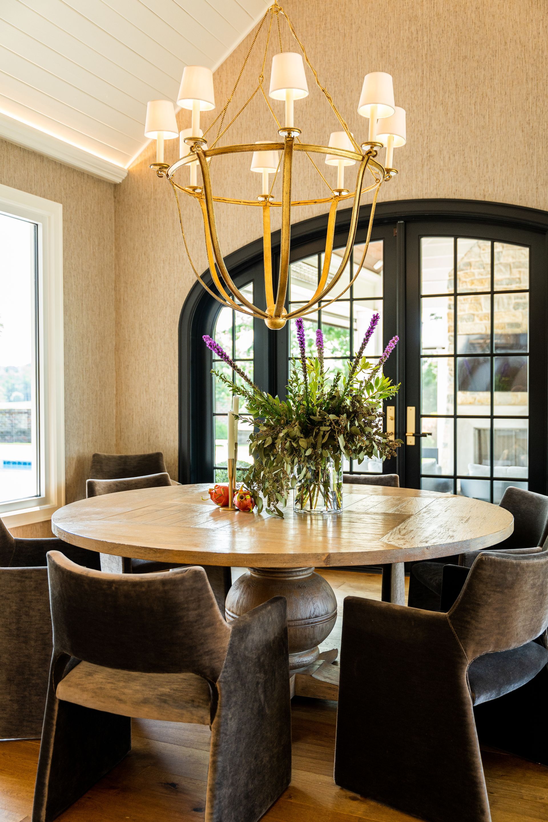 A dining room with a round table and chairs and a chandelier.