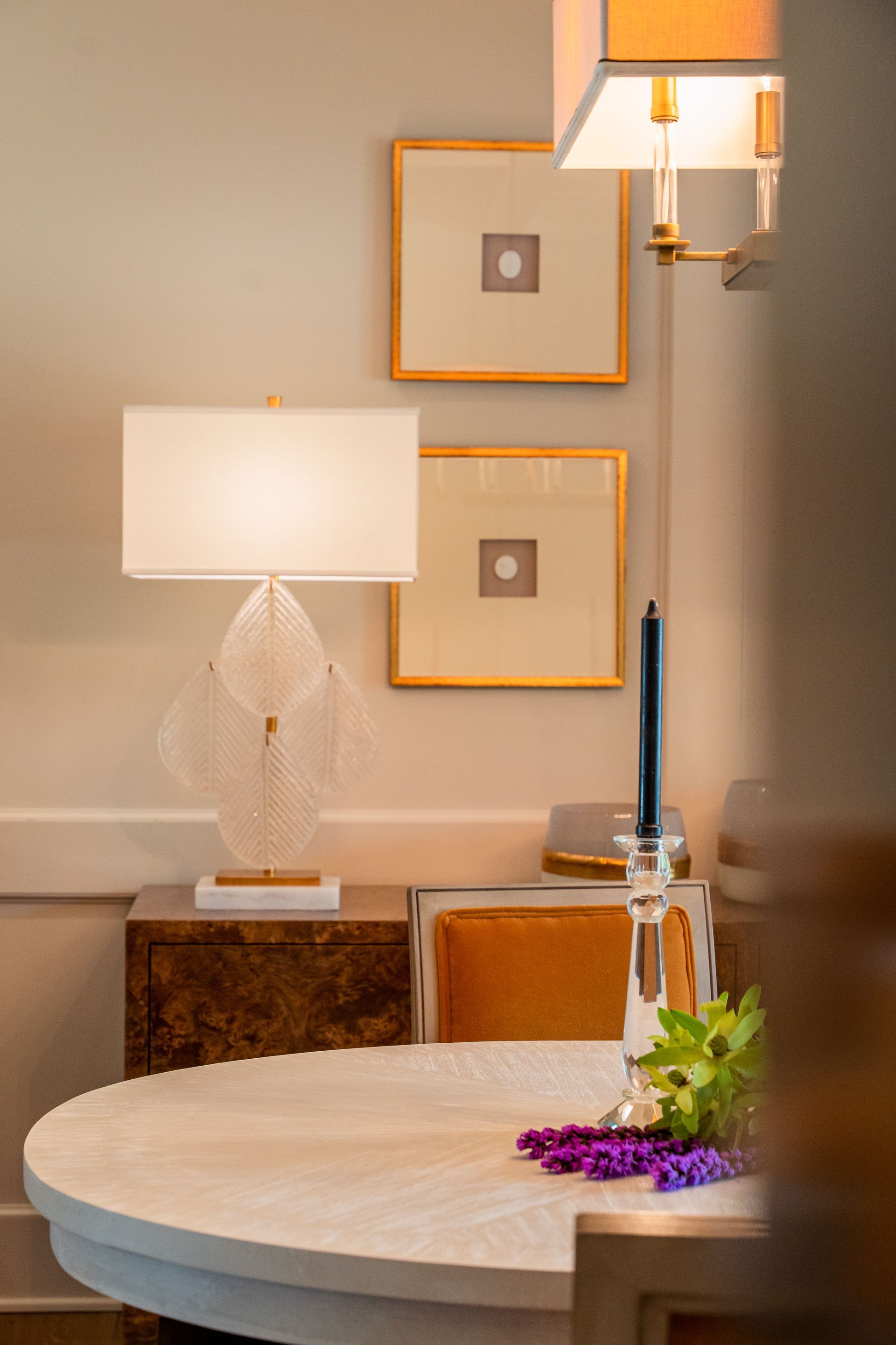 A table with a lamp and a candle on it in a room.