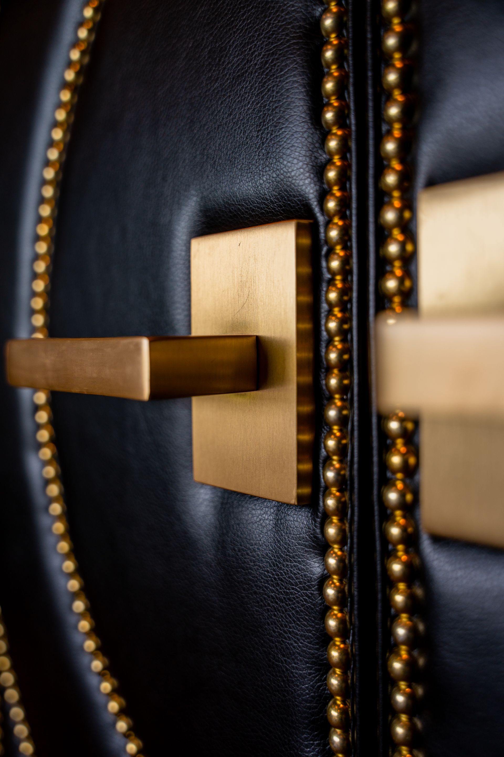 A close up of a gold door handle on a black door.