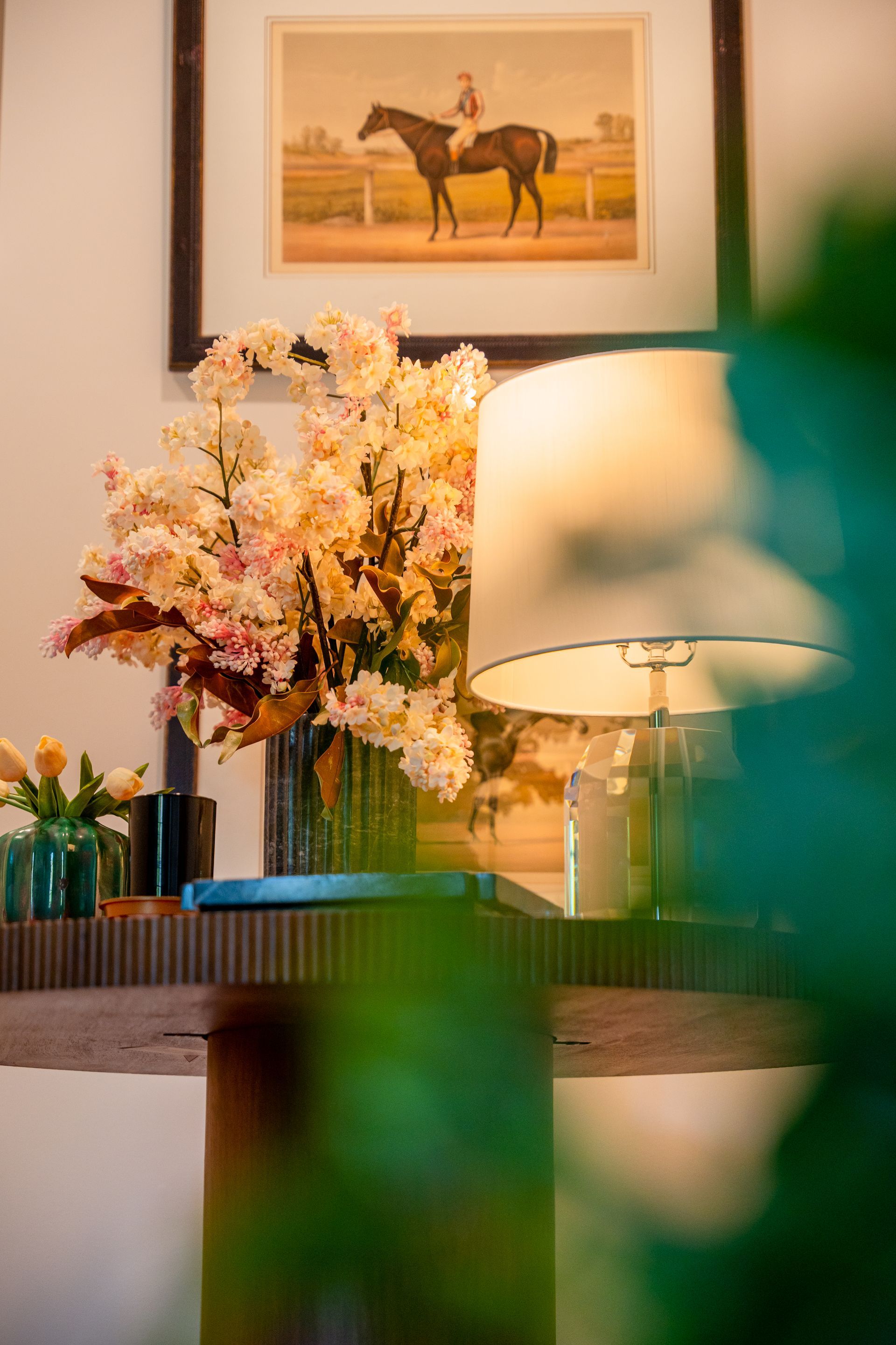 A lamp is sitting on a table next to a vase of flowers.