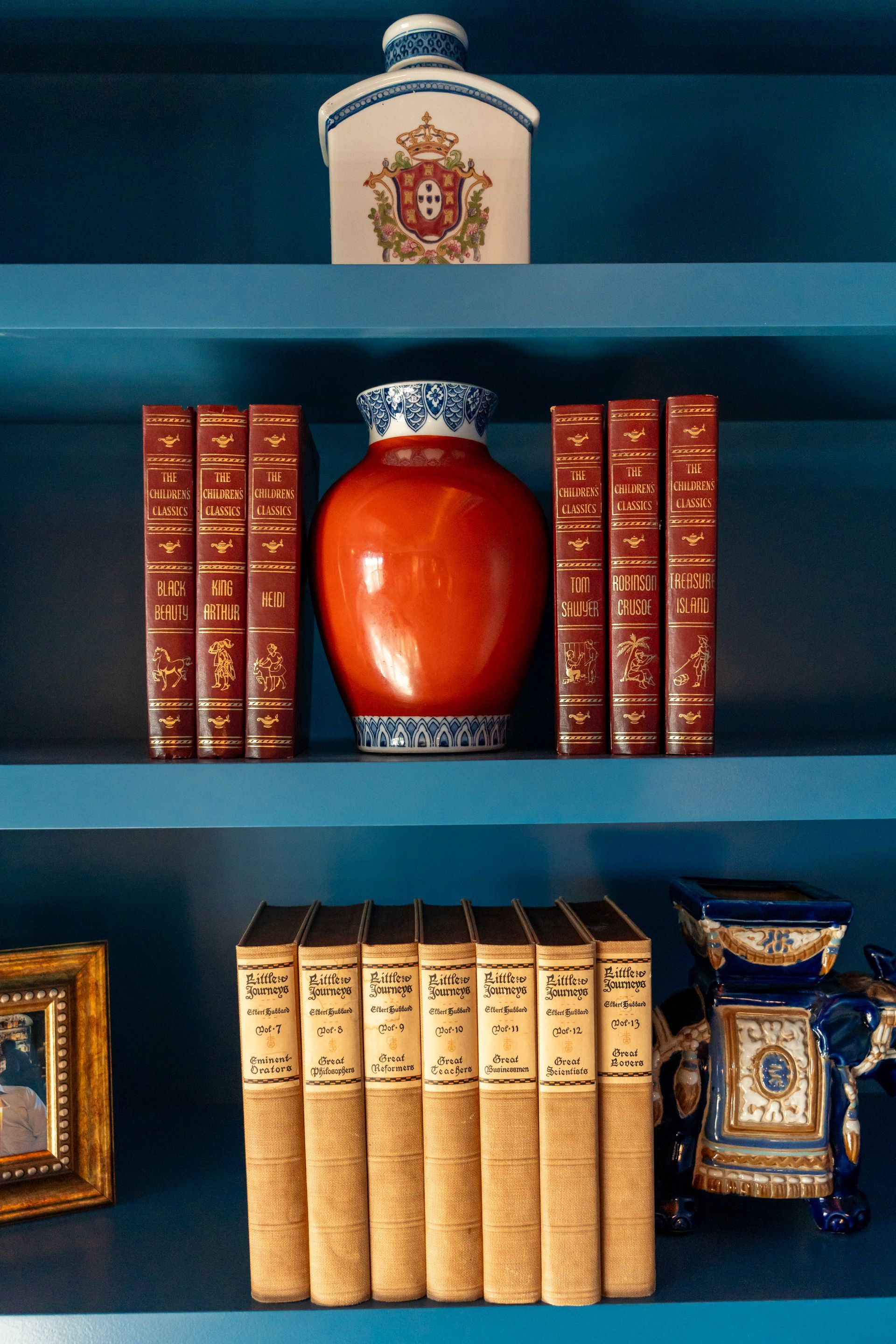 A blue bookshelf with a vase and books on it