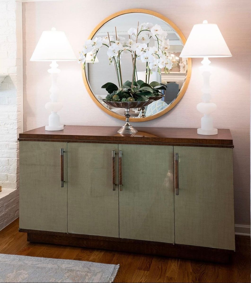 A dresser with a vase of flowers and a mirror above it