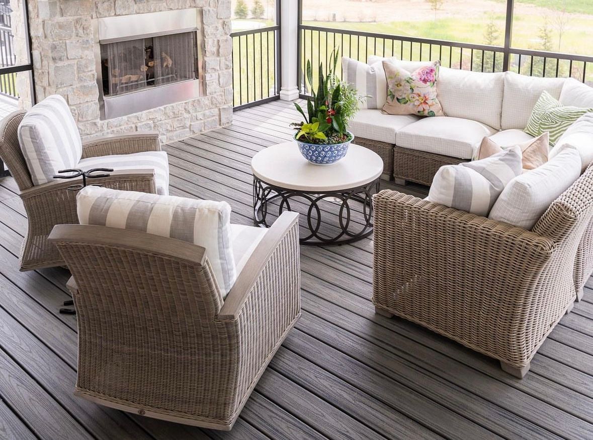 A screened in porch with wicker furniture and a fireplace.
