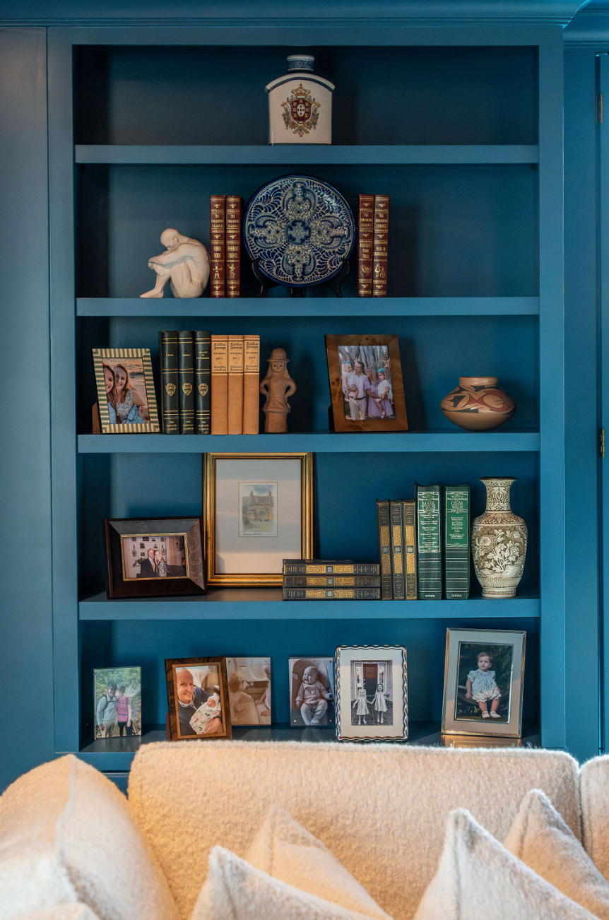 A living room with blue shelves filled with books , pictures and vases.