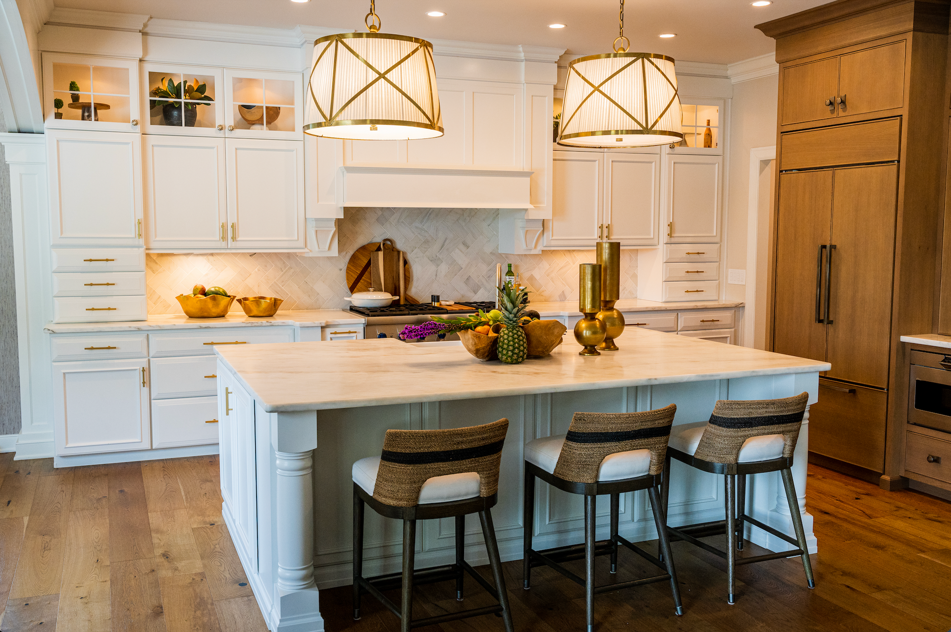 A kitchen with white cabinets , a large island , and wicker chairs.