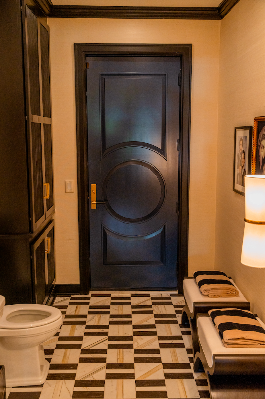 A bathroom with a blue door , a toilet , and a checkered floor.