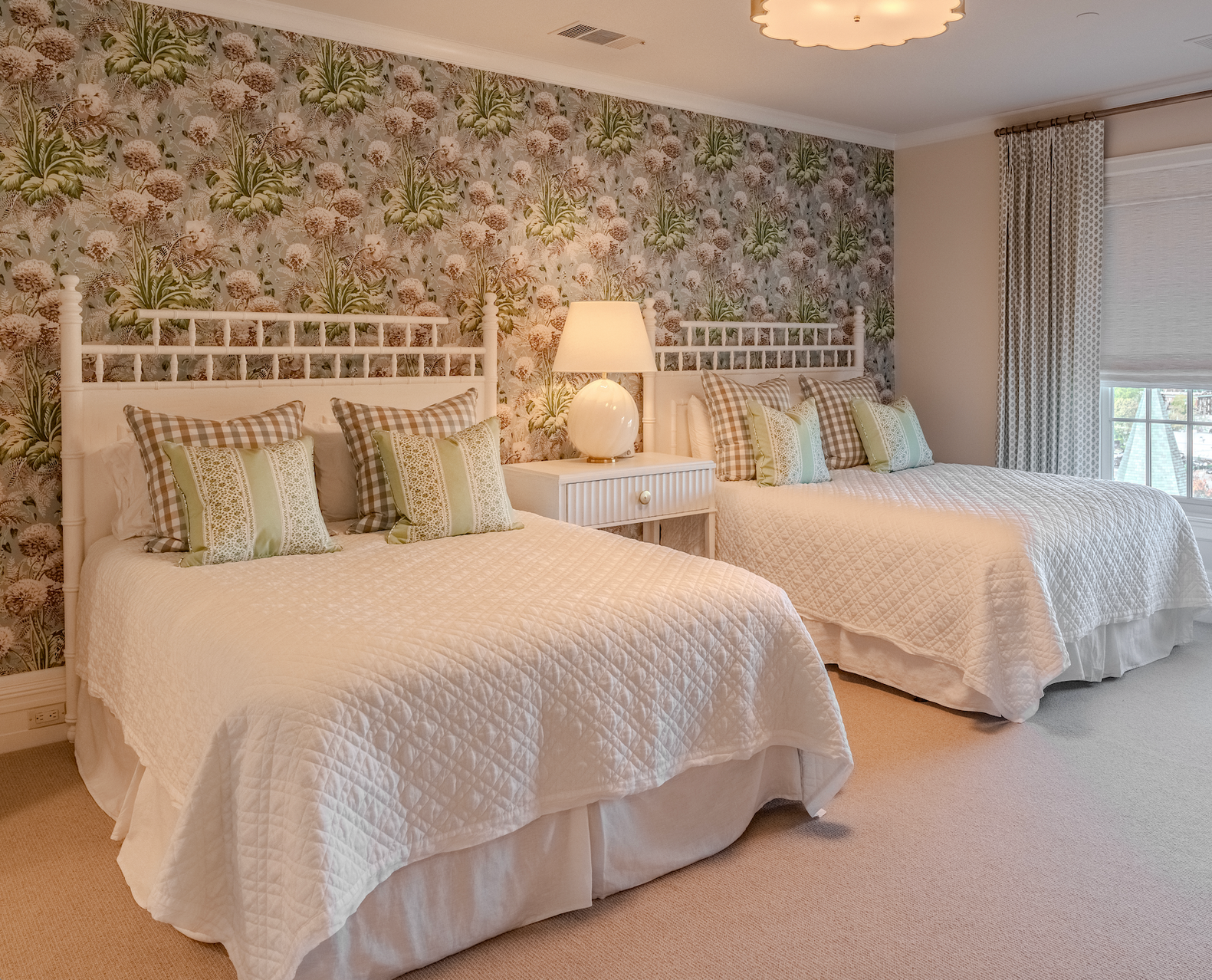 A bedroom with two beds and a floral wallpaper